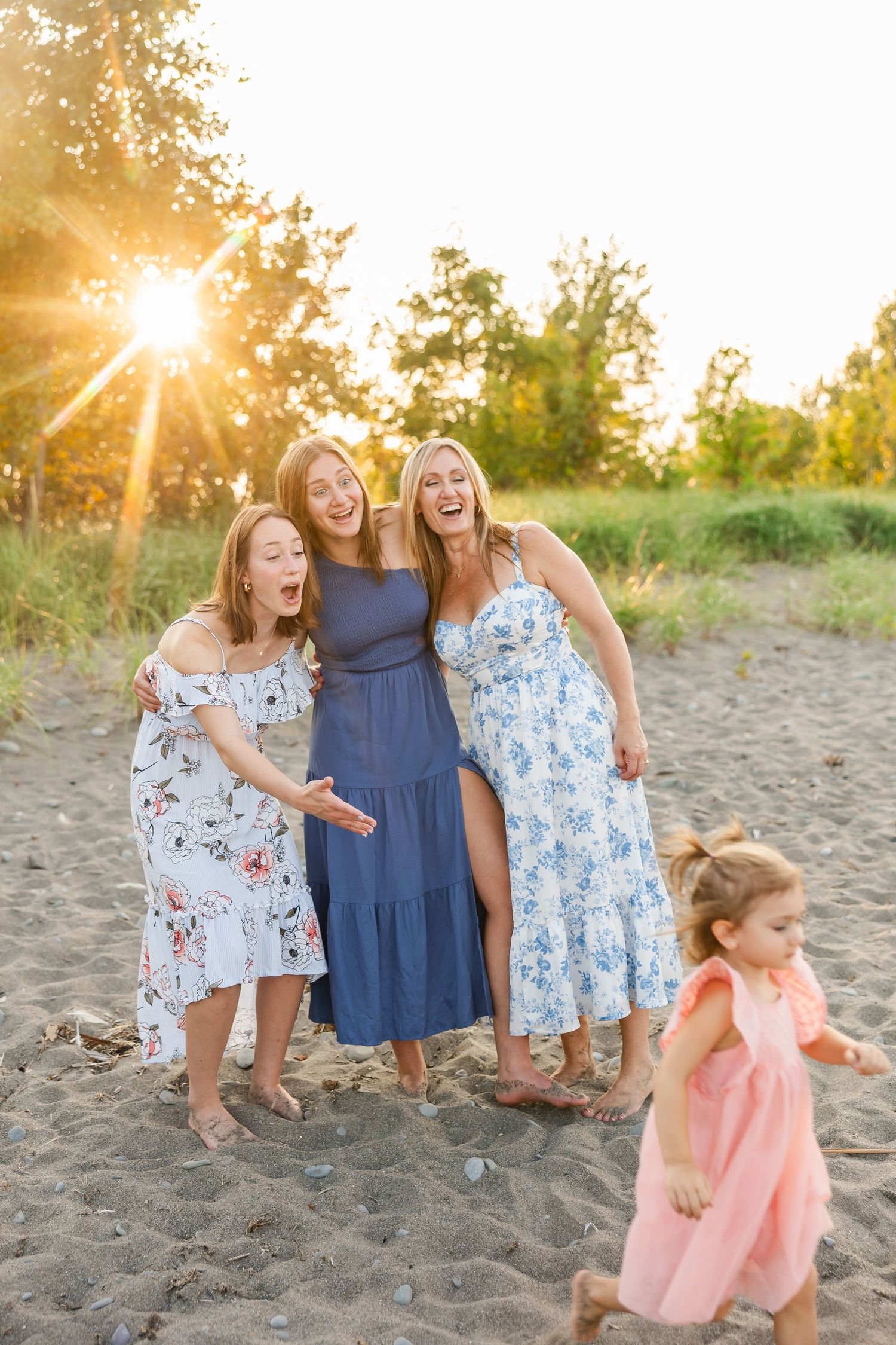 A group enjoying a sunset moment together on a sandy beach while wearing summer dresses.