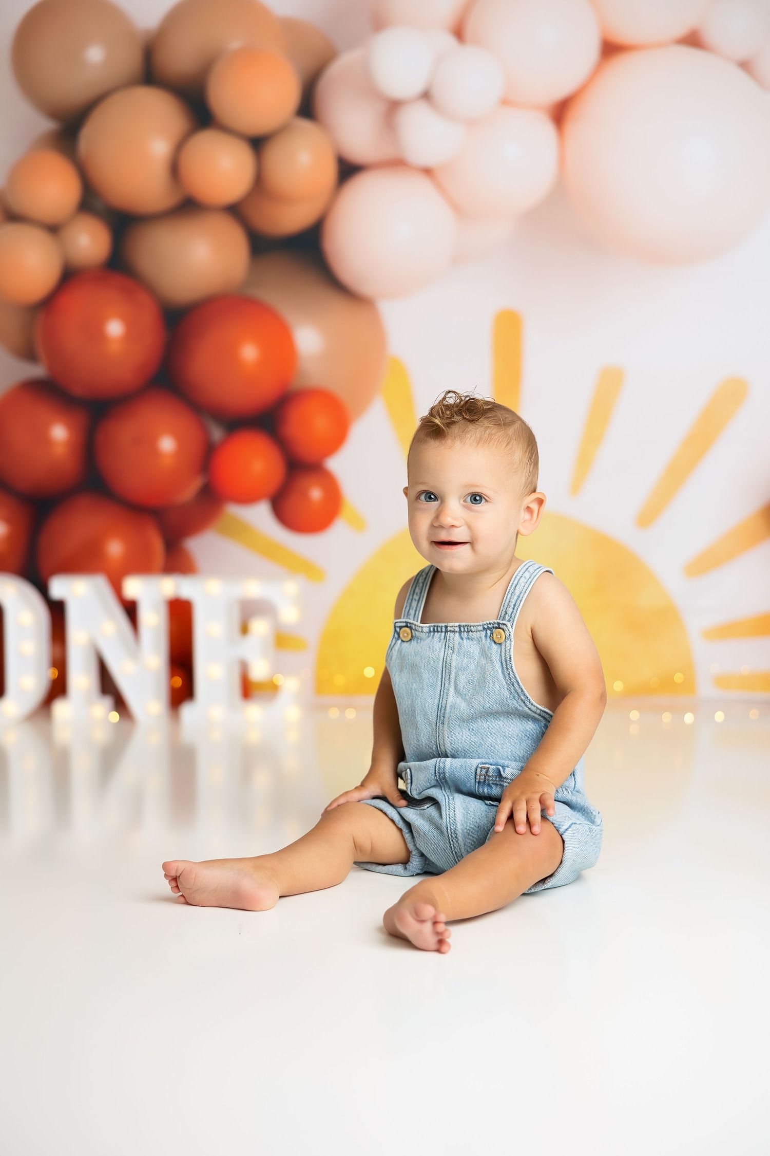 Birthday photo setup featuring warm-toned balloon decor and a bright yellow sun design.