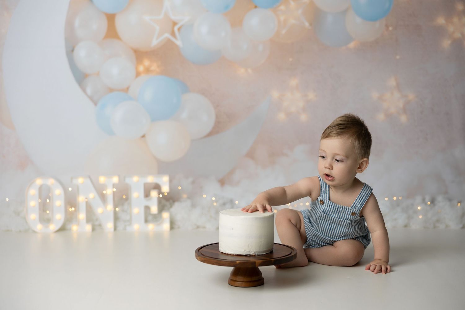 Photography collage showing first birthday cake smash session with blue and white balloons and decorative backdrop.