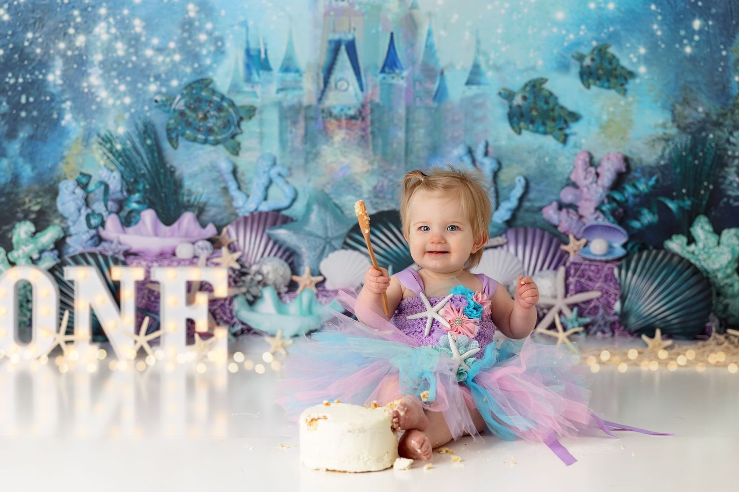 Enchanted underwater themed first birthday setup with seashells and castle backdrop.