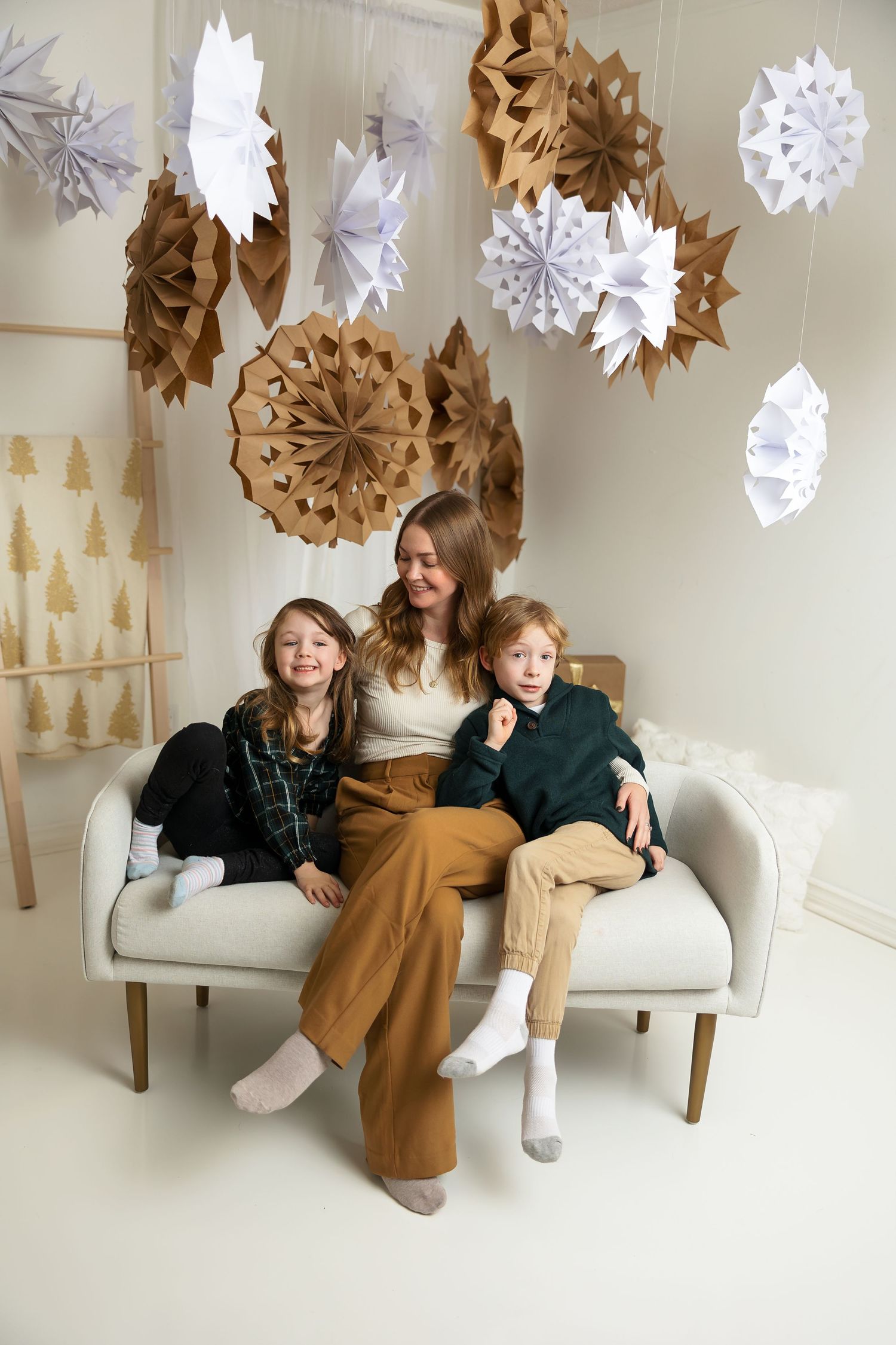 Casual indoor family portrait with brown and white paper decorations hanging above.