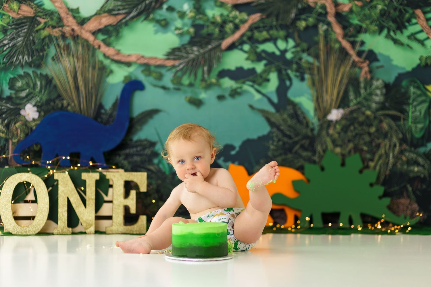 Jungle themed first birthday setup with tropical leaves and peacock decorations.