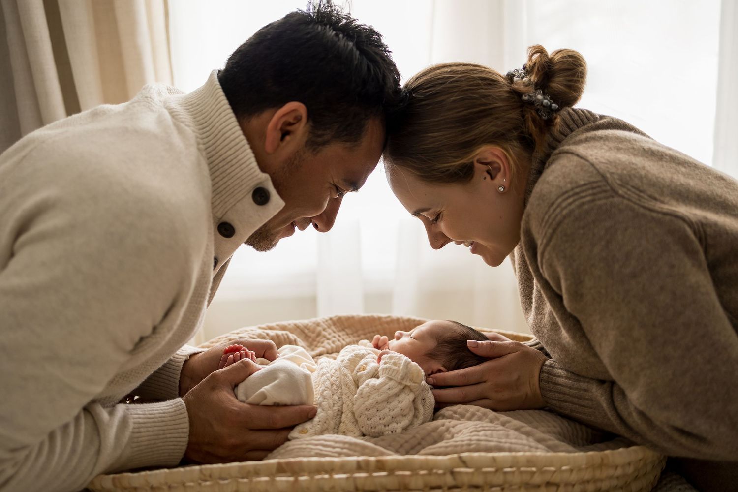 New parents lovingly gaze at their newborn baby in a cozy nursery setting.