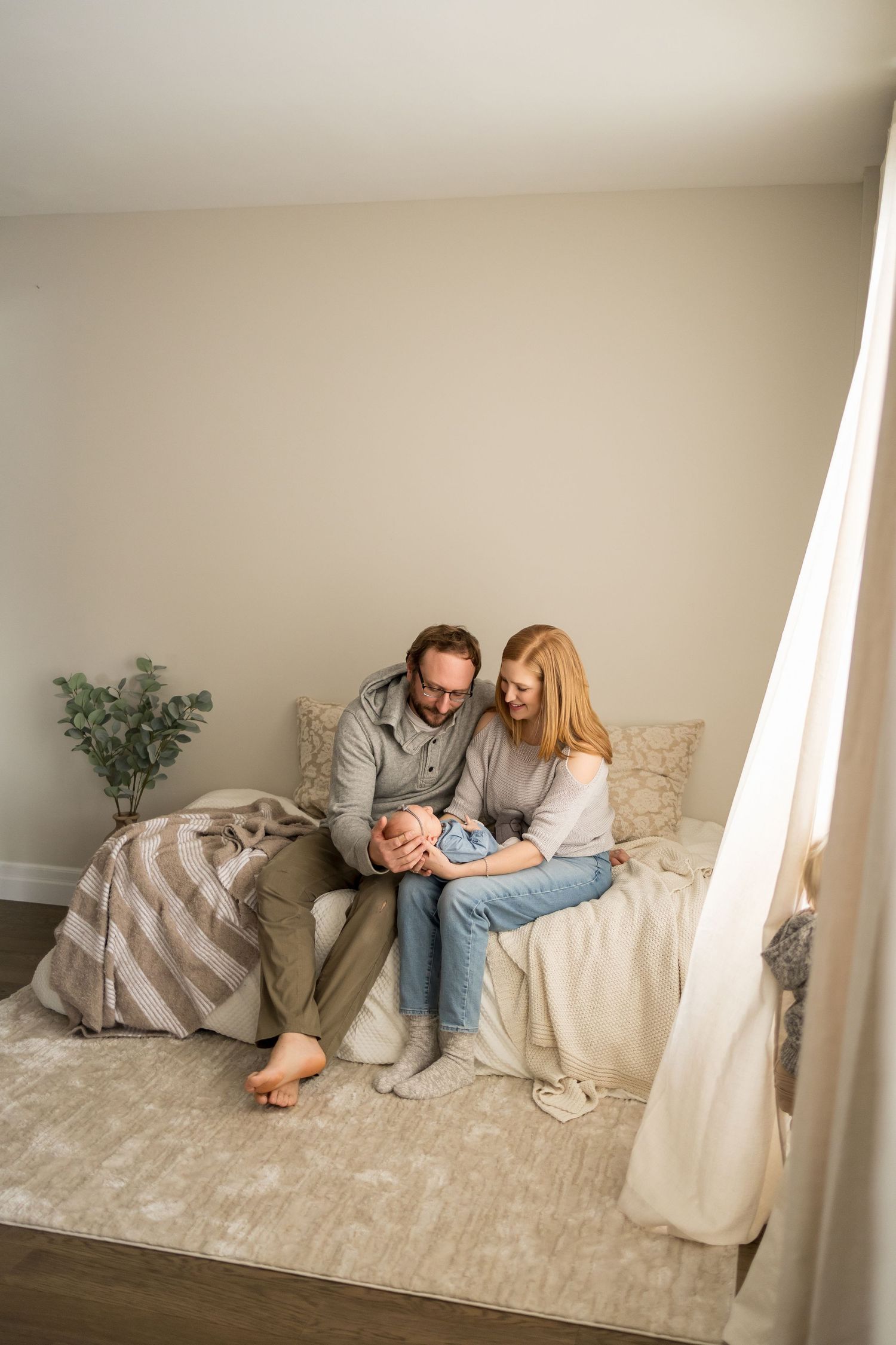 A couple relaxes together on a beige carpeted floor against a white wall in a minimalist setting.