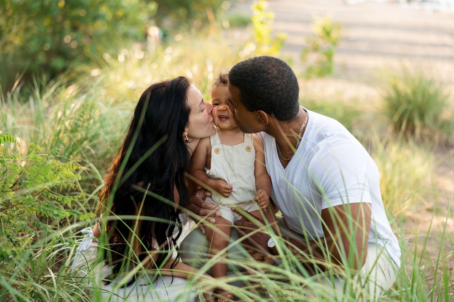 An intimate family moment captured in tall grass during golden hour.