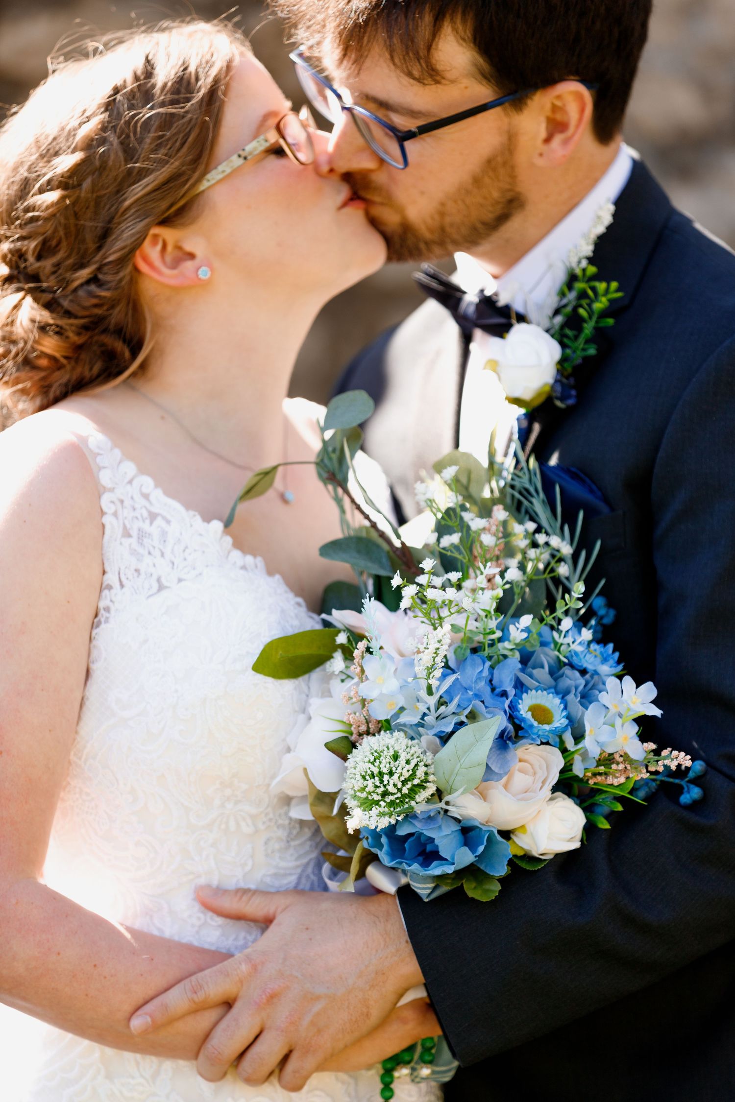 Close-up wedding portrait with blue and white bouquet against natural lighting.