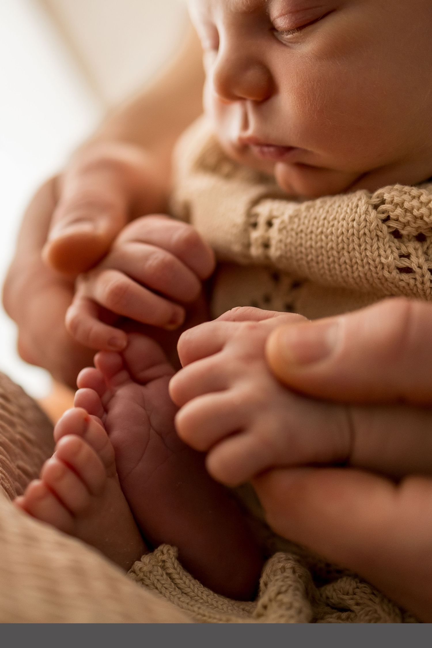 Close up view of tiny baby feet wrapped in soft knitted blanket in warm natural lighting.