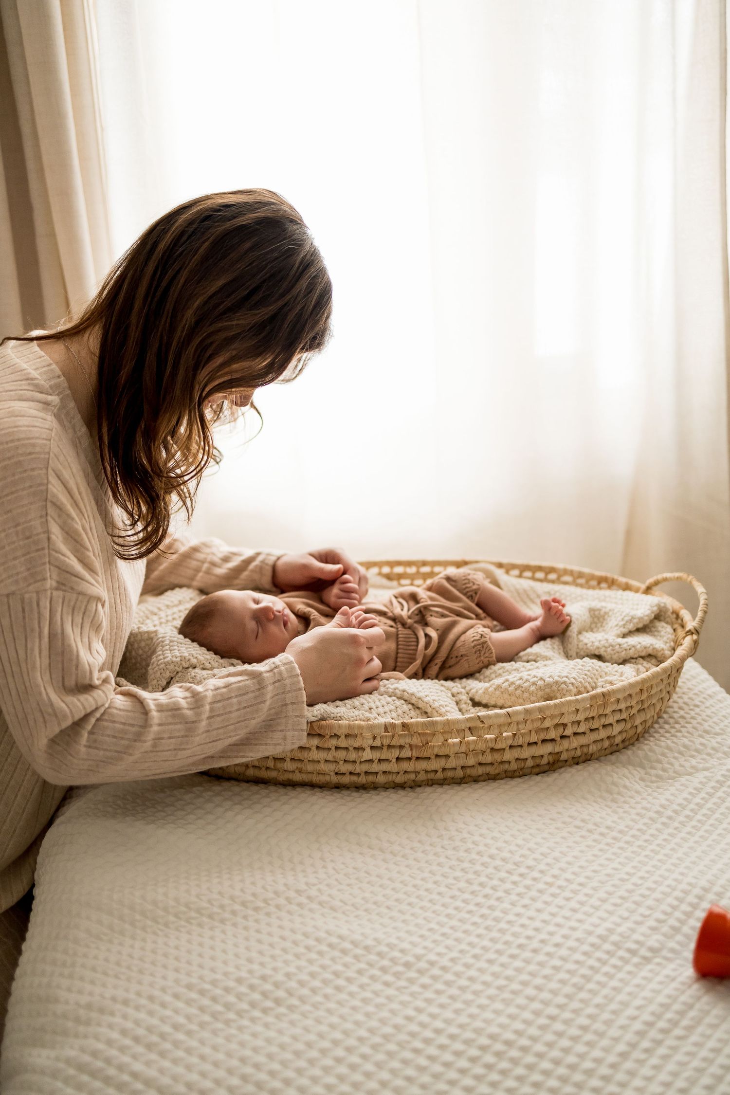 A collection of lifestyle photos showing a parent tending to their baby in a woven basket on a white textured surface.
