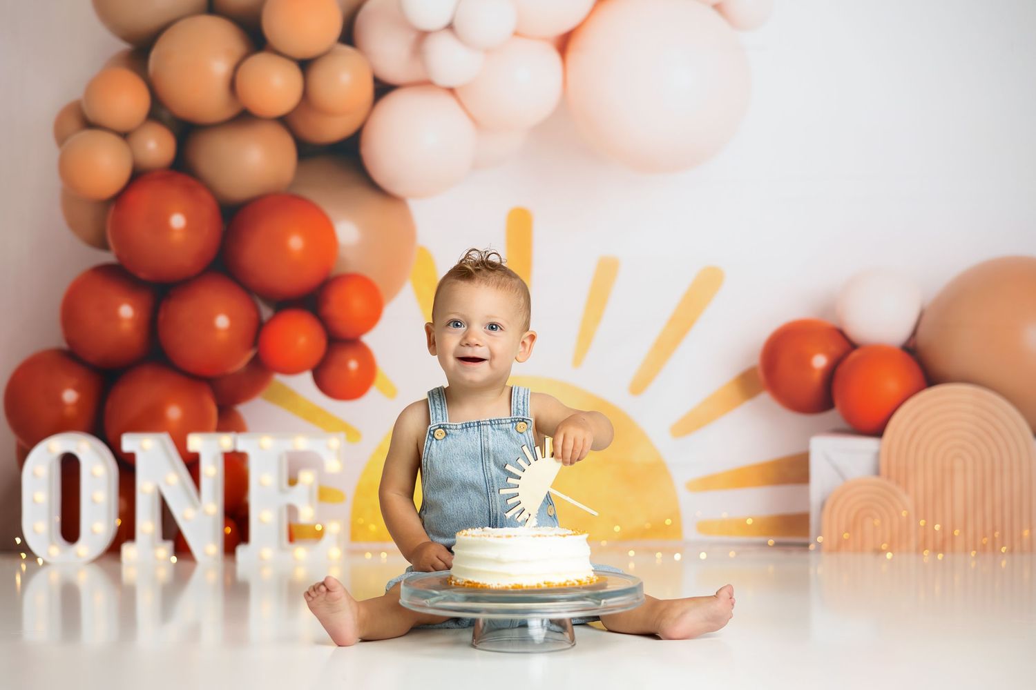 Birthday celebration setup with white cake and orange-toned balloon arrangement.
