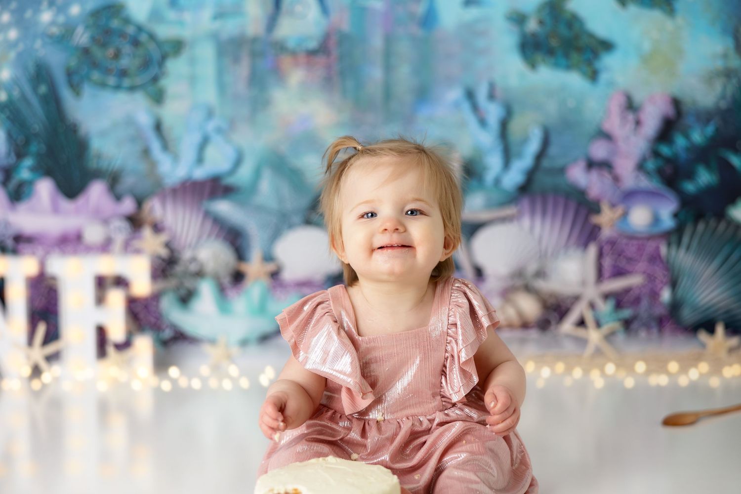 First birthday photo shoot with cake and dreamy underwater castle background.