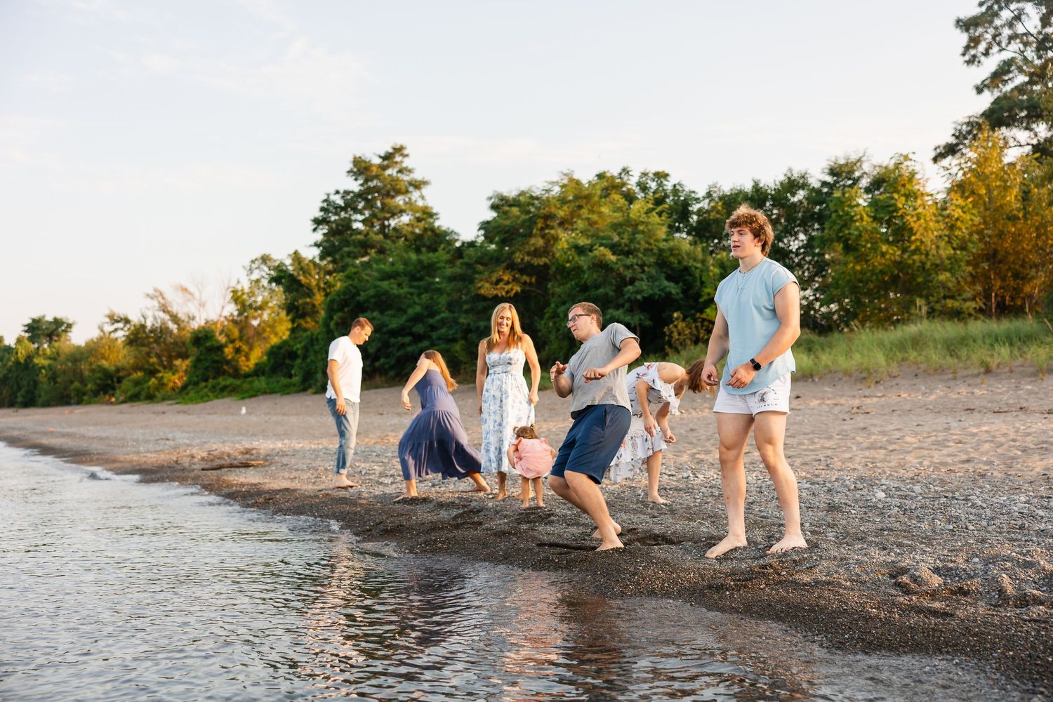 A group enjoys a sunset walk along the shoreline of a beach on a warm summer evening.