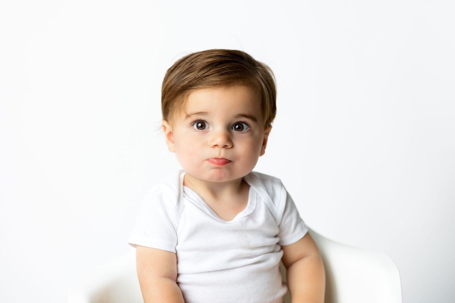 Baby wearing white t-shirt during minimalist studio photo session.