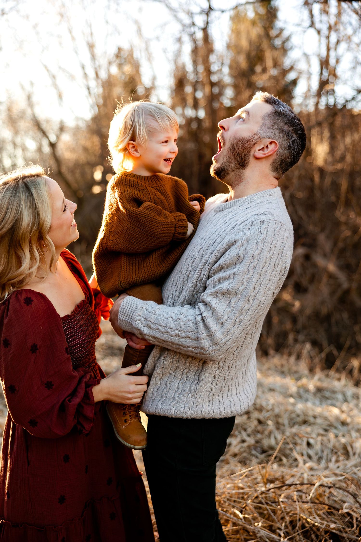 A joyful family shares a laughing moment together in warm evening sunlight.
