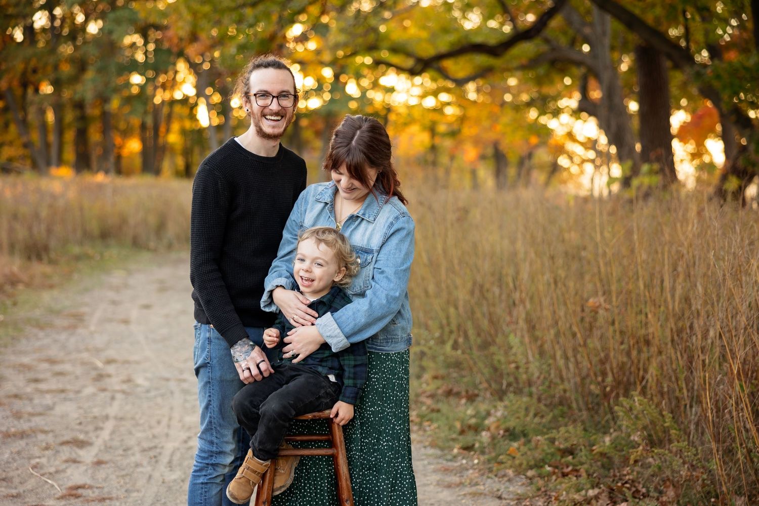 A family shares a warm moment together on a path during golden hour in autumn.
