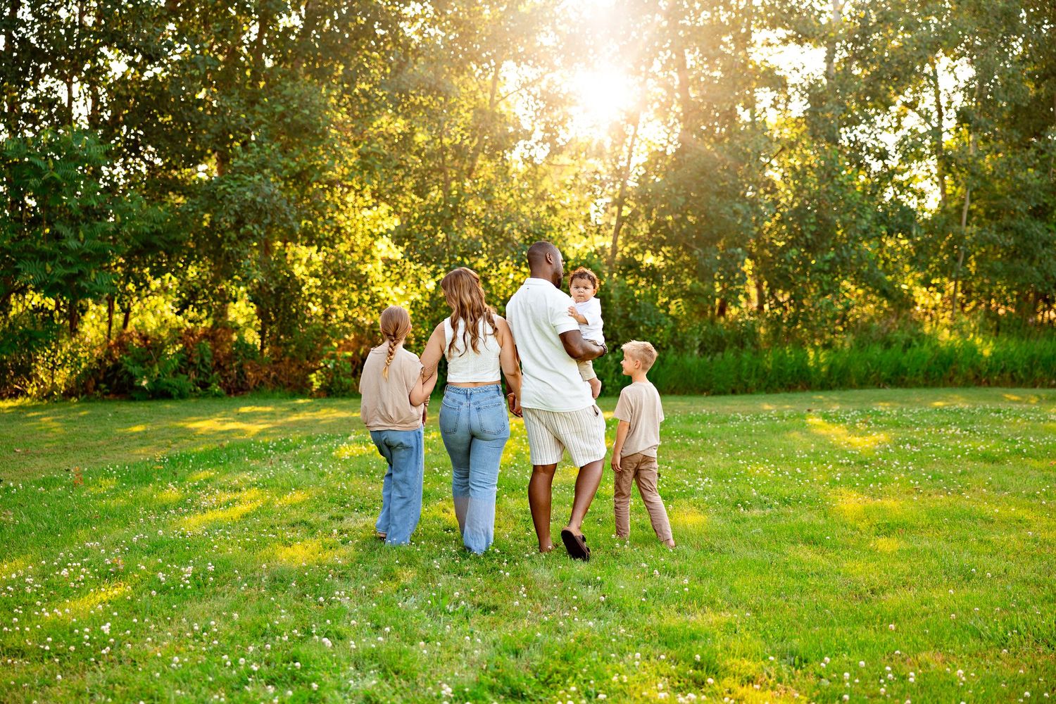 A family walking together on green grass during sunset.