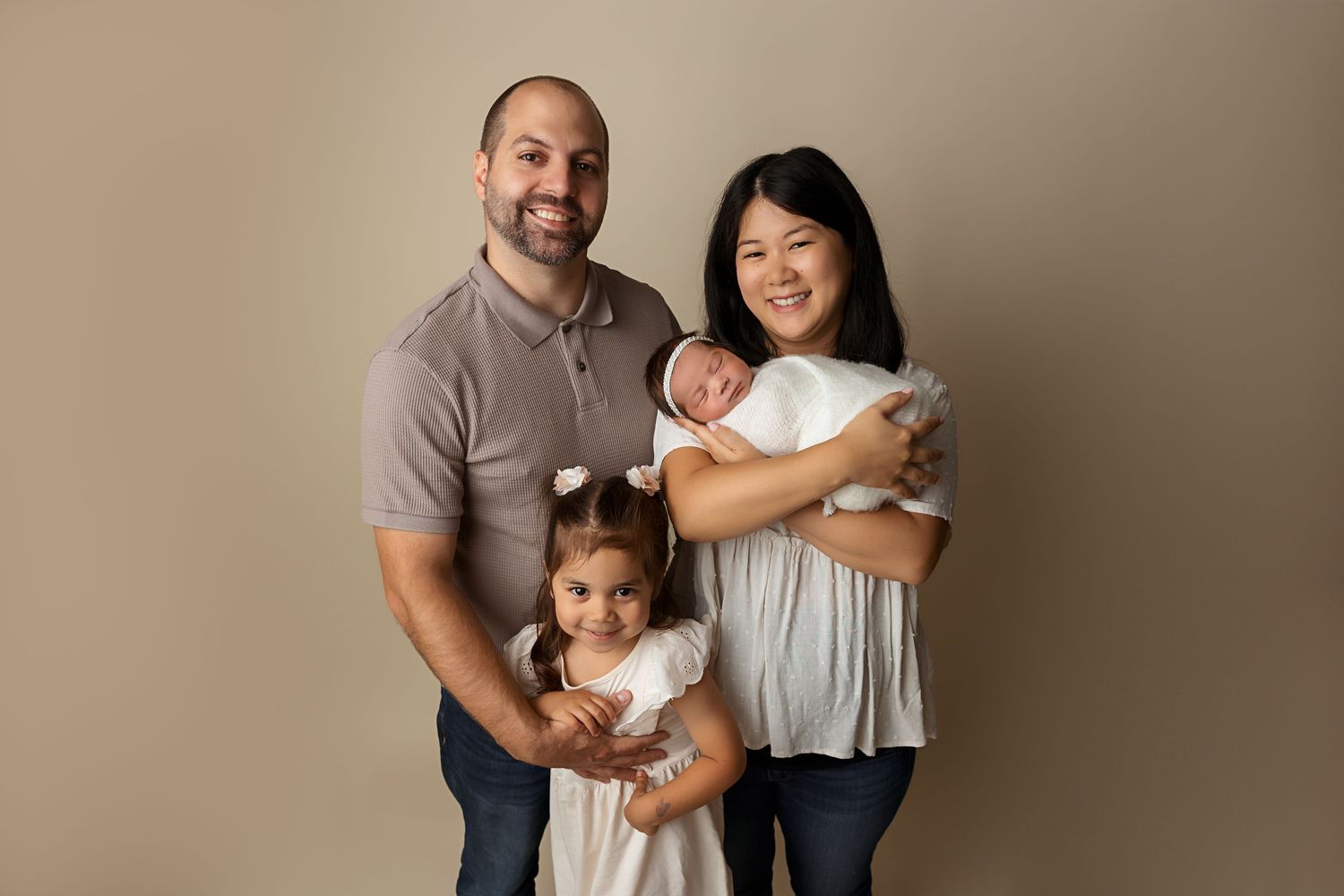 A heartwarming family portrait against a neutral studio backdrop.