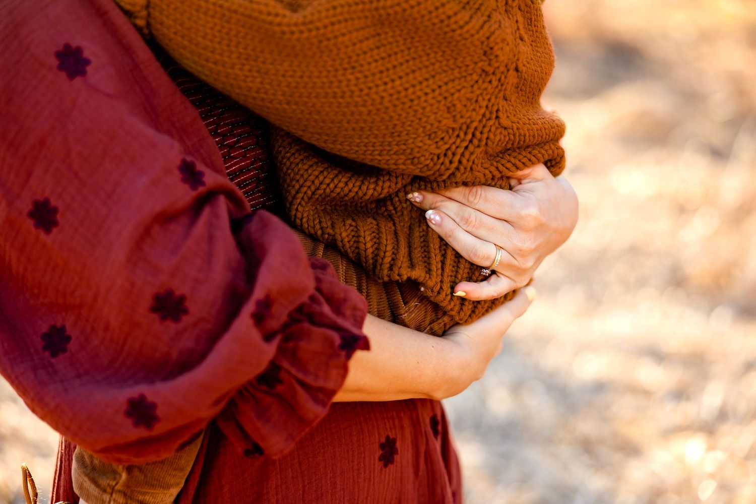 Close-up detail of a burgundy polka dot dress and brown knit sweater in warm autumn lighting.