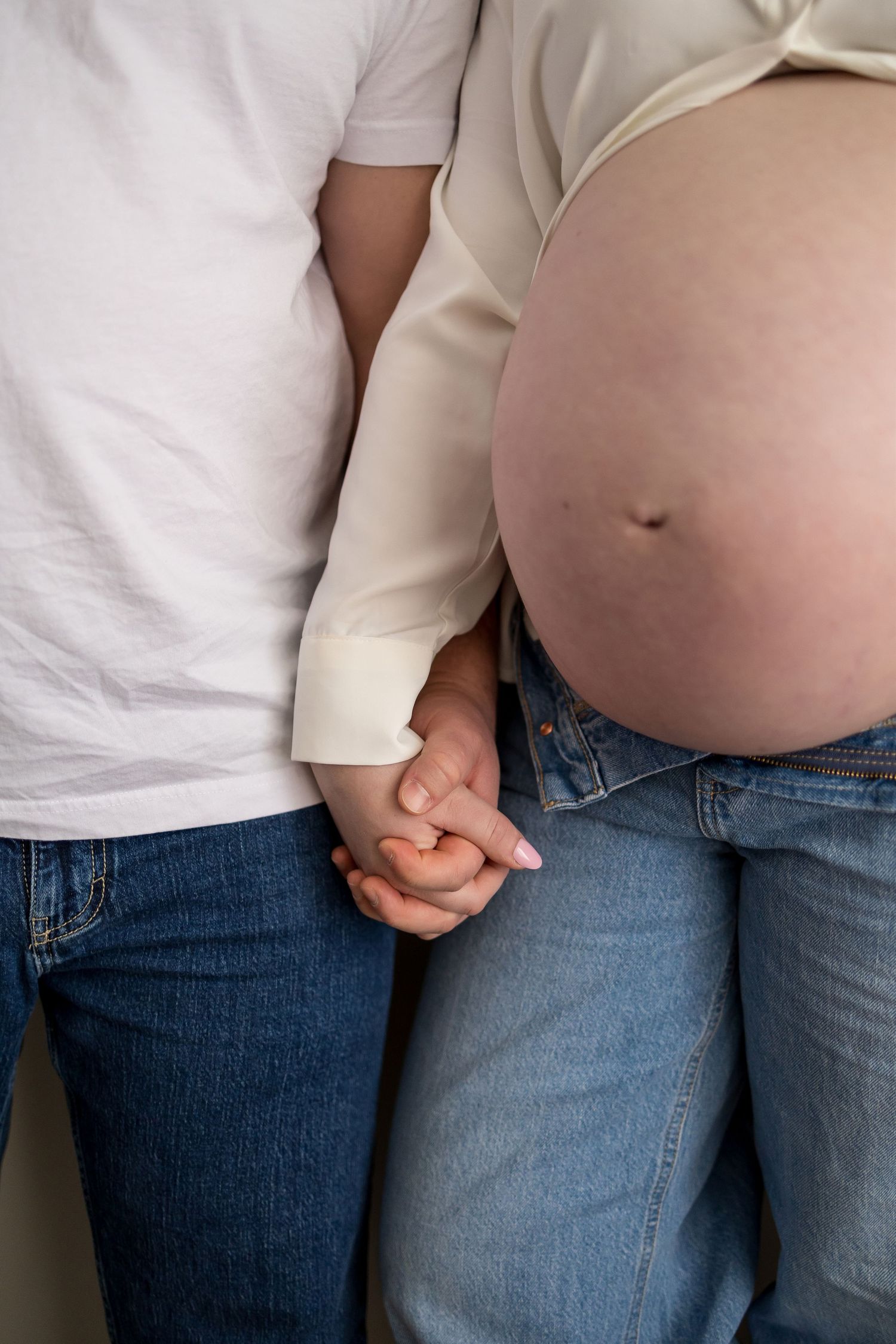 A series of progress photos showing a growing baby bump during pregnancy in blue jeans and white shirt.