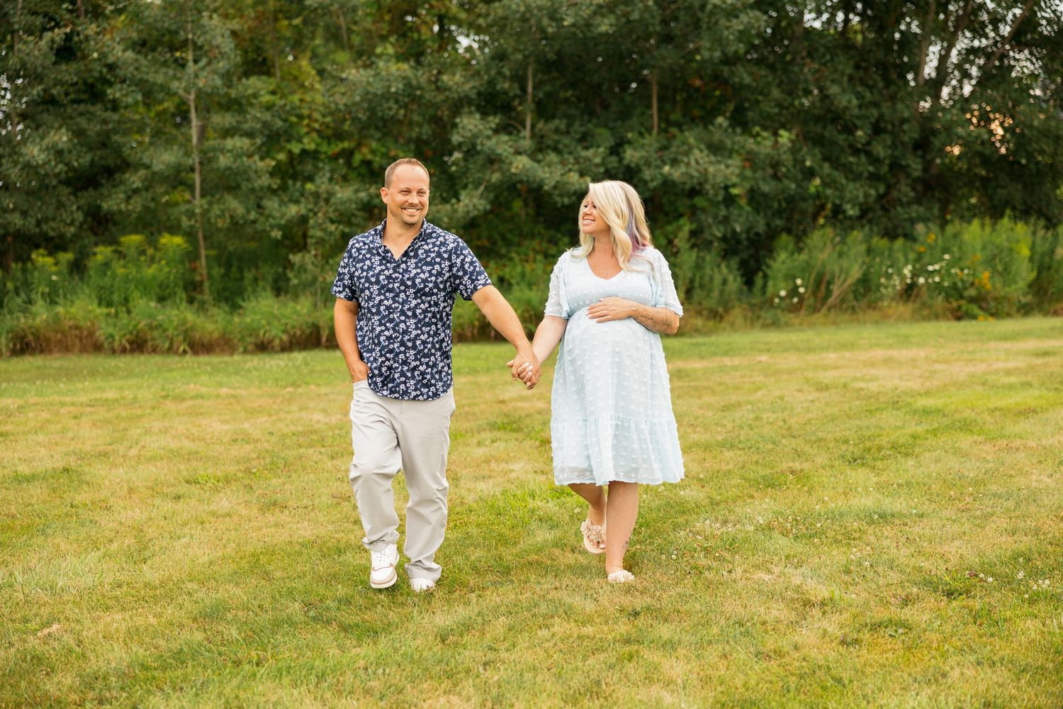 Couple enjoying a romantic outdoor photo session in a lush green field on a sunny day.