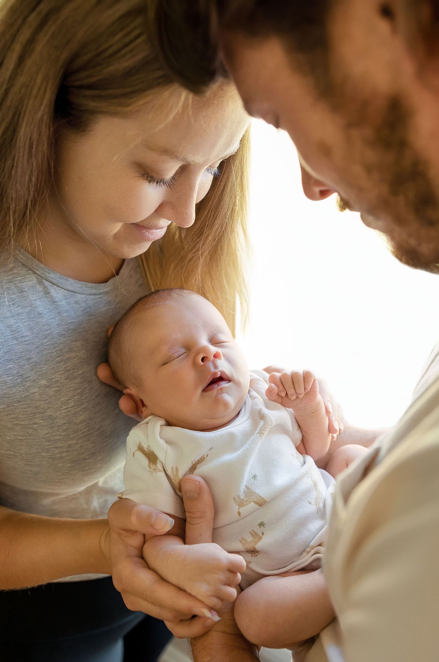 Parents share tender moments with their newborn baby in a series of intimate close-up photographs.