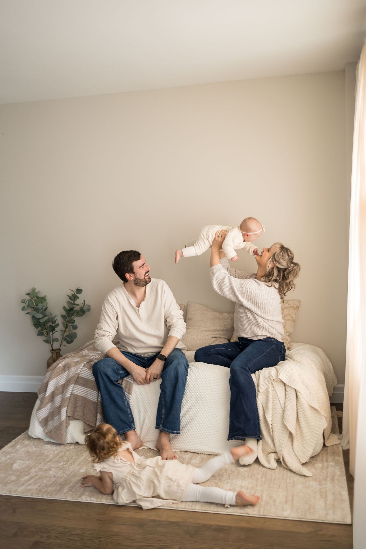 Playful family moments captured on a white couch showing casual lifestyle interaction.