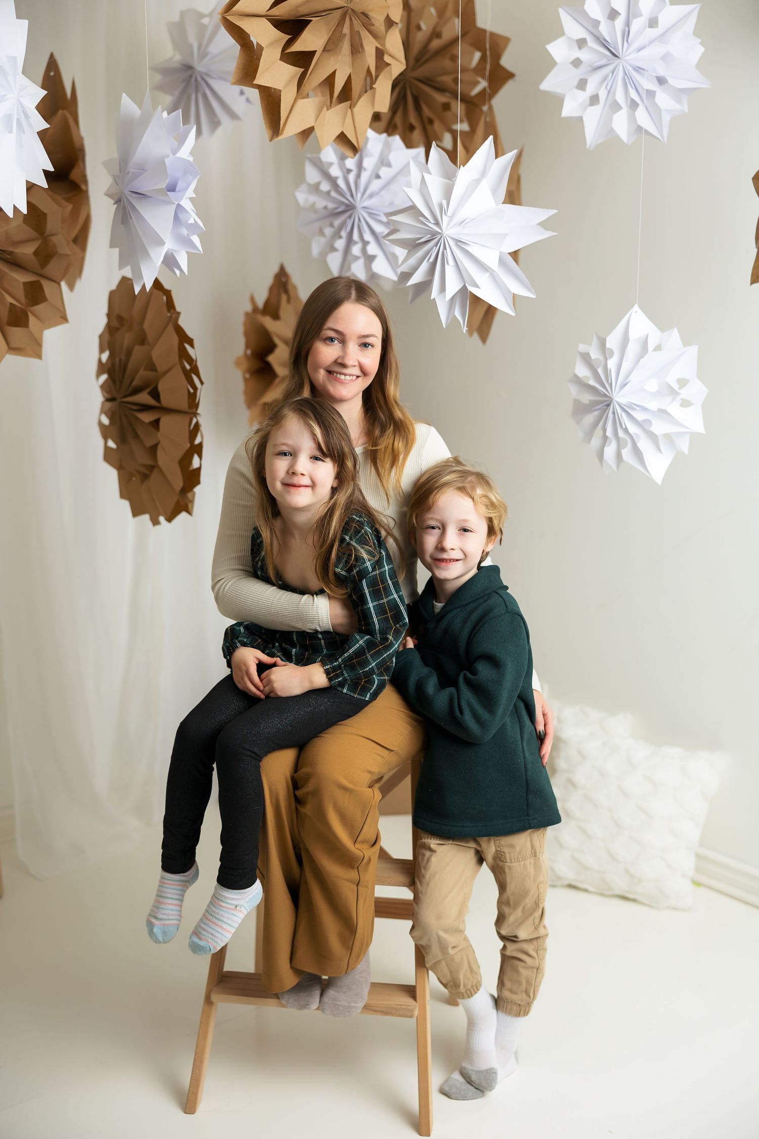 Indoor winter portrait with decorative paper snowflakes hanging from ceiling.