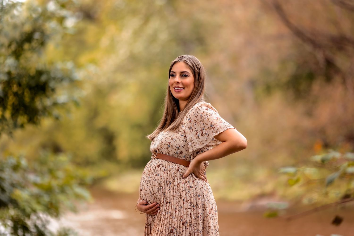 An expectant mother in a sparkly dress poses outdoors during a maternity photoshoot.