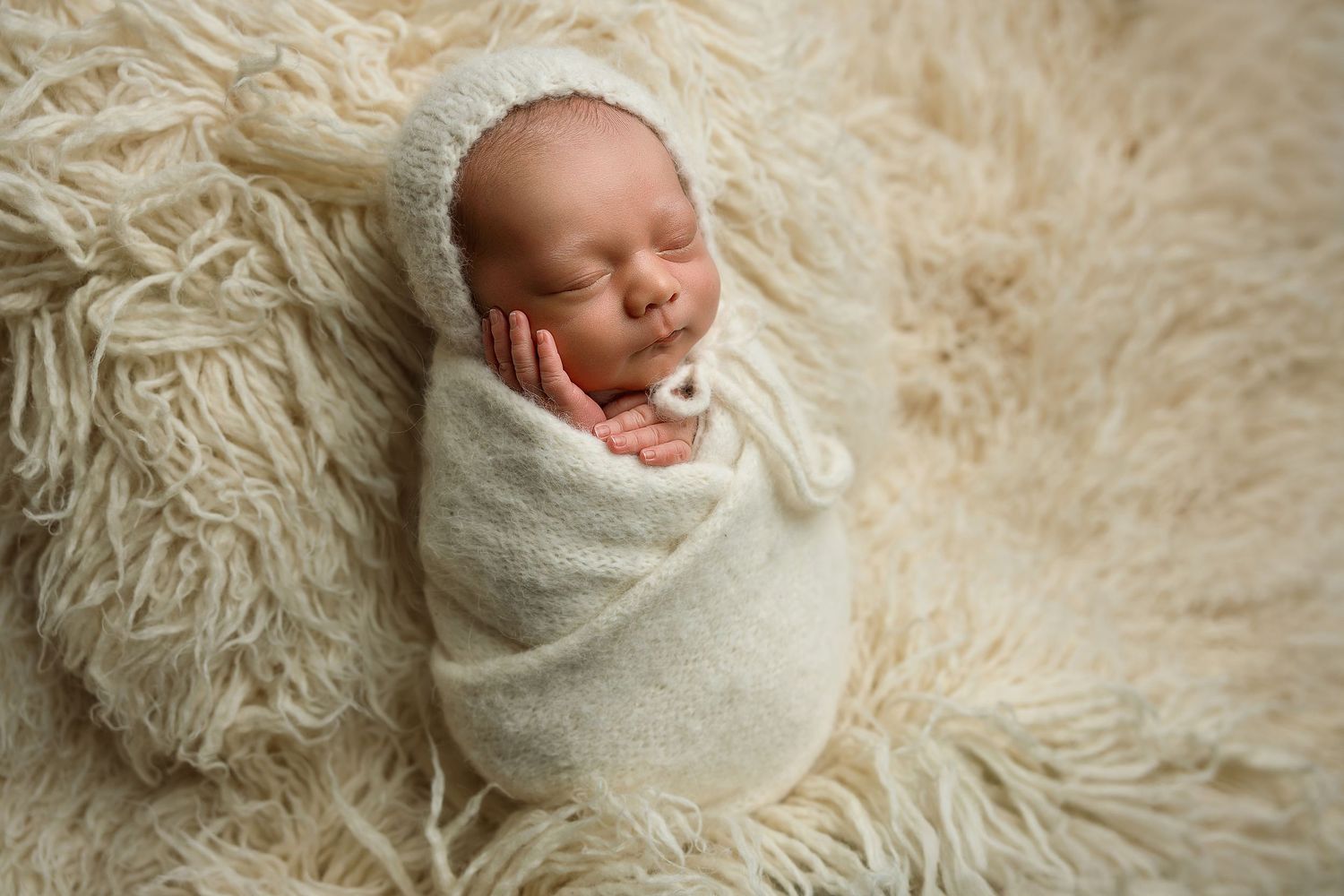 Swaddled baby wearing a soft delicate bonnet on a neutral backdrop, Images by LeBlanc photography studio.