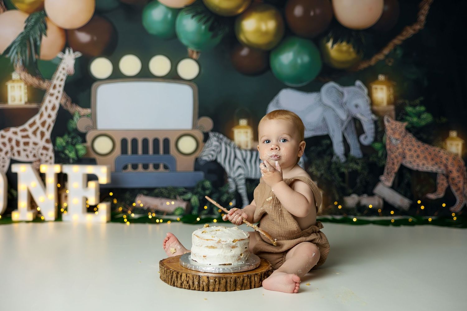 Safari themed first birthday party setup with balloons, decorations, and jungle animal motifs in green and gold colors.