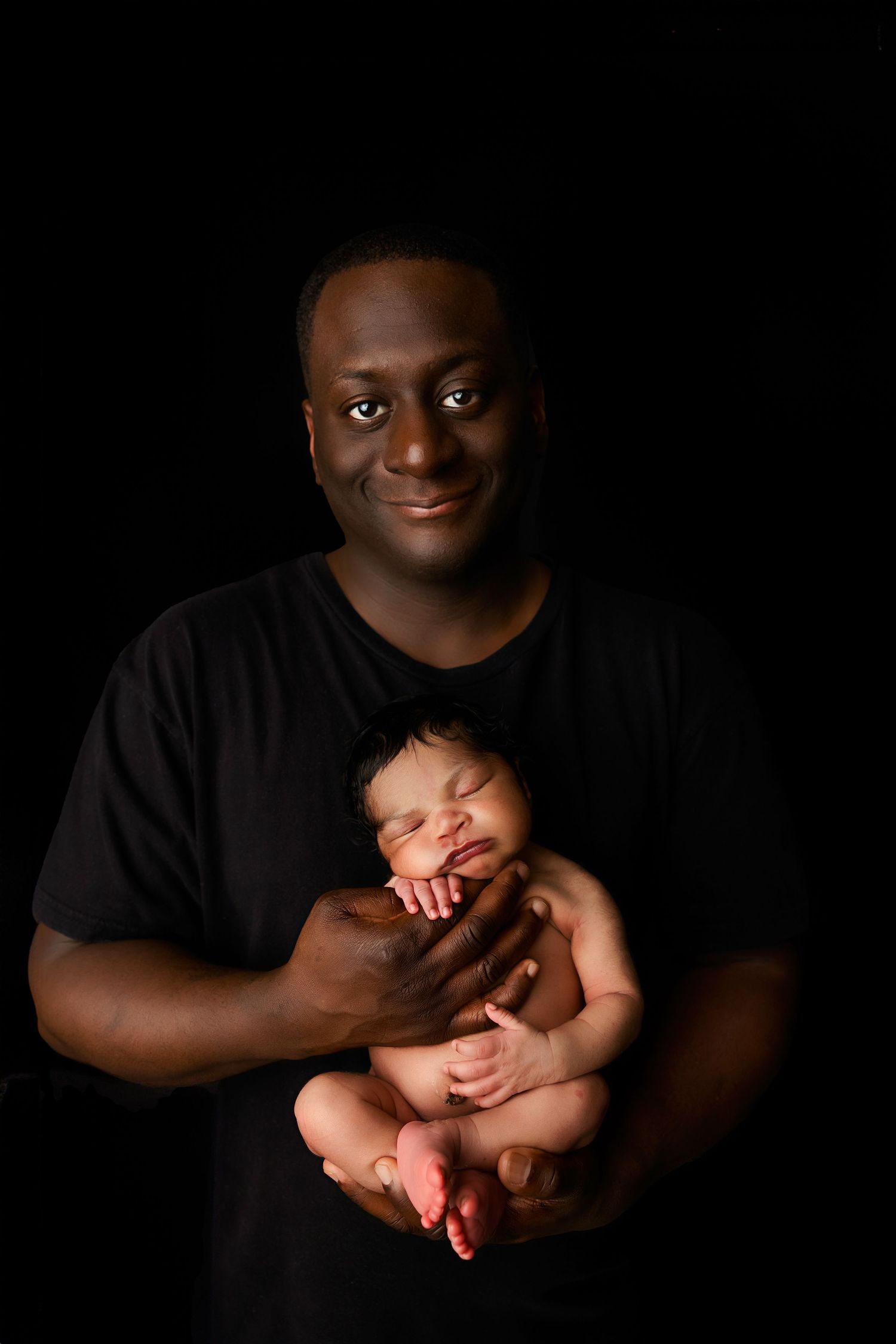 A series of dark and moody photographs showing tender moments between a parent cradling a sleeping newborn baby.