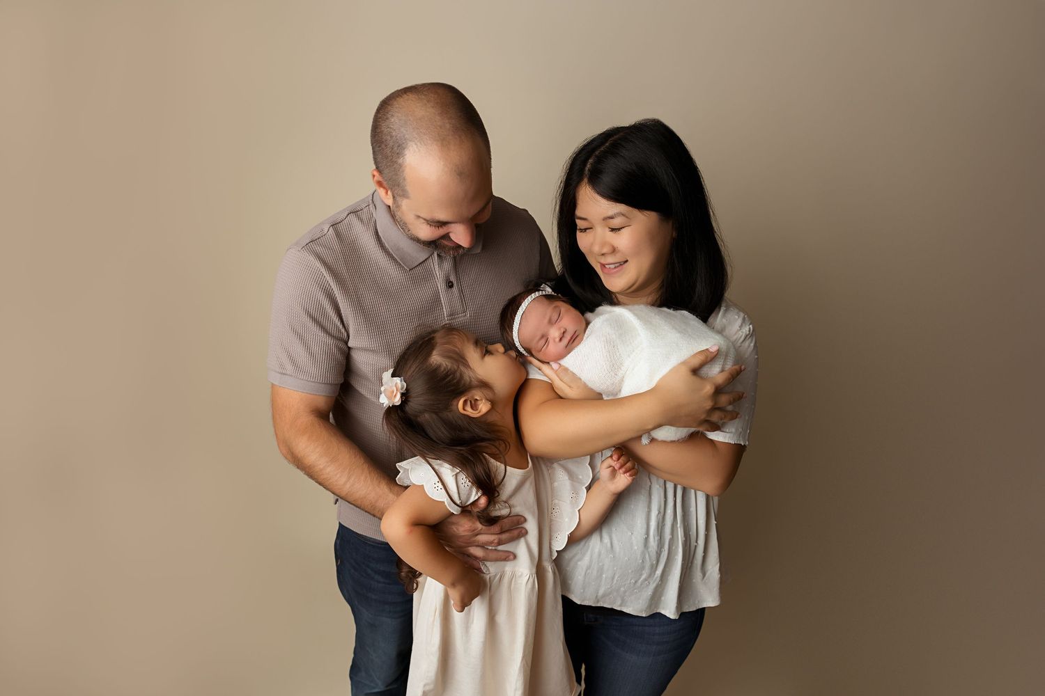 A warm family portrait including a beloved pet against a neutral backdrop.