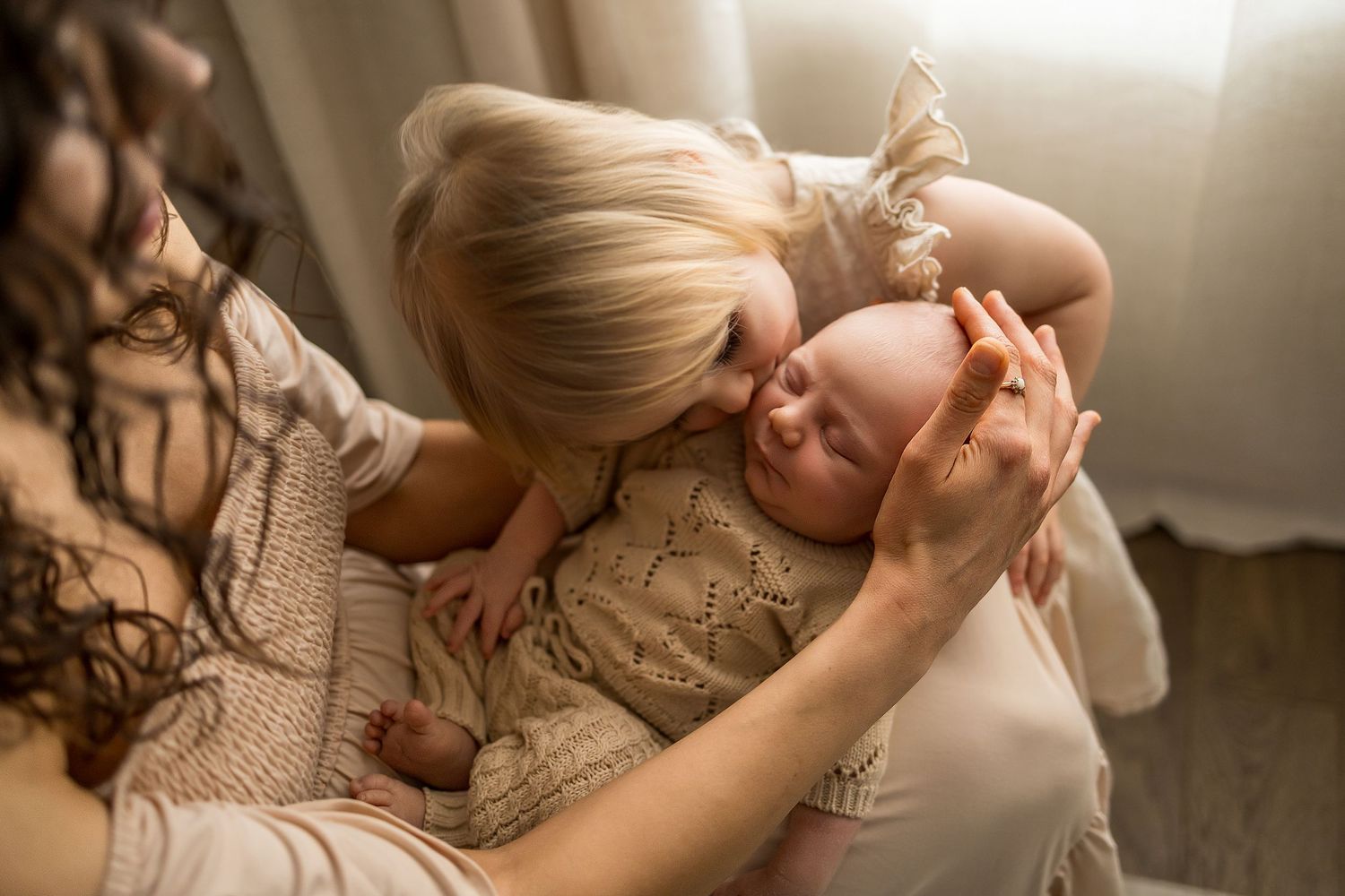 A tender moment captured in warm light as a parent in a cozy sweater snuggles with their baby.