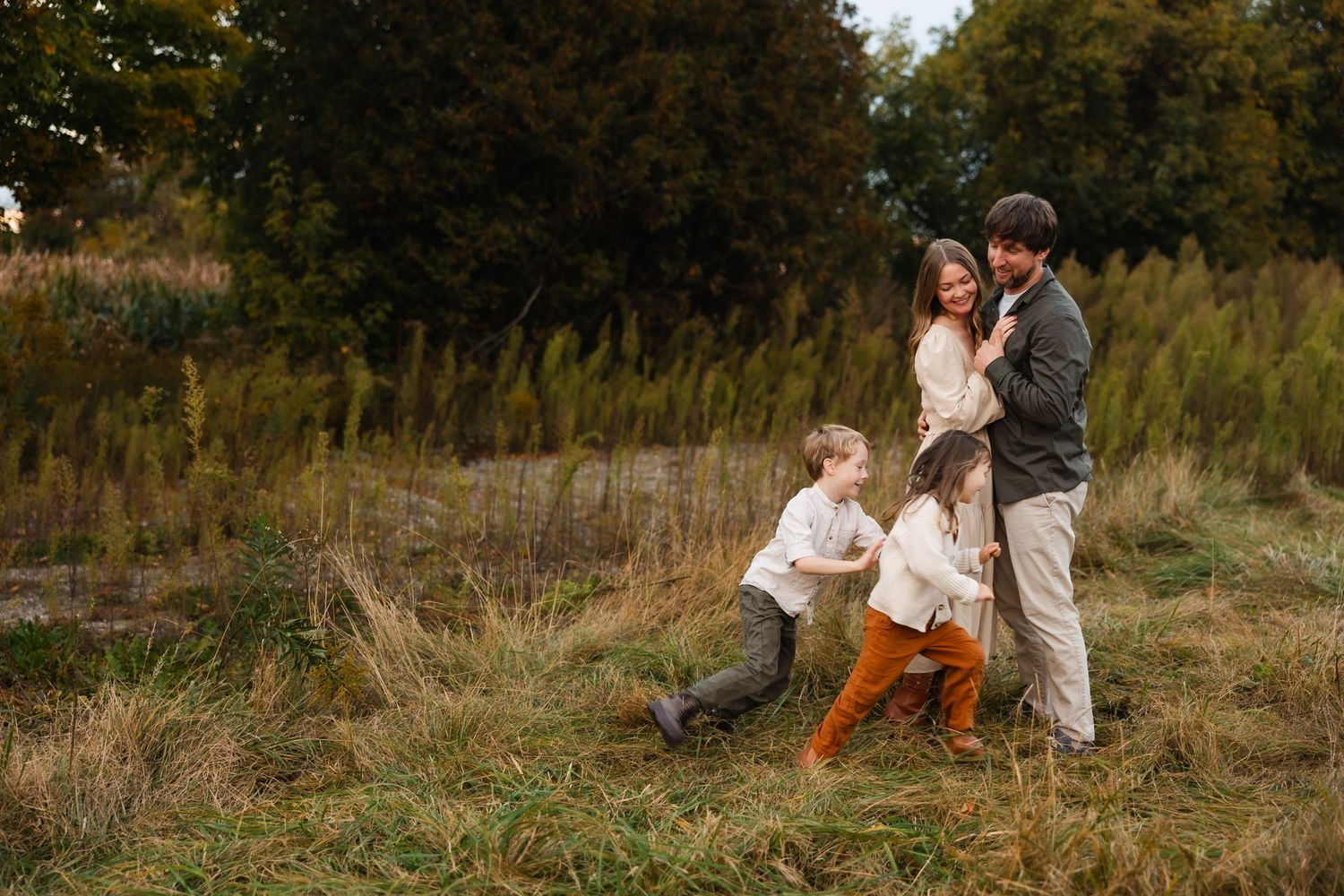 A playful family moment captured in a rustic field during golden hour.