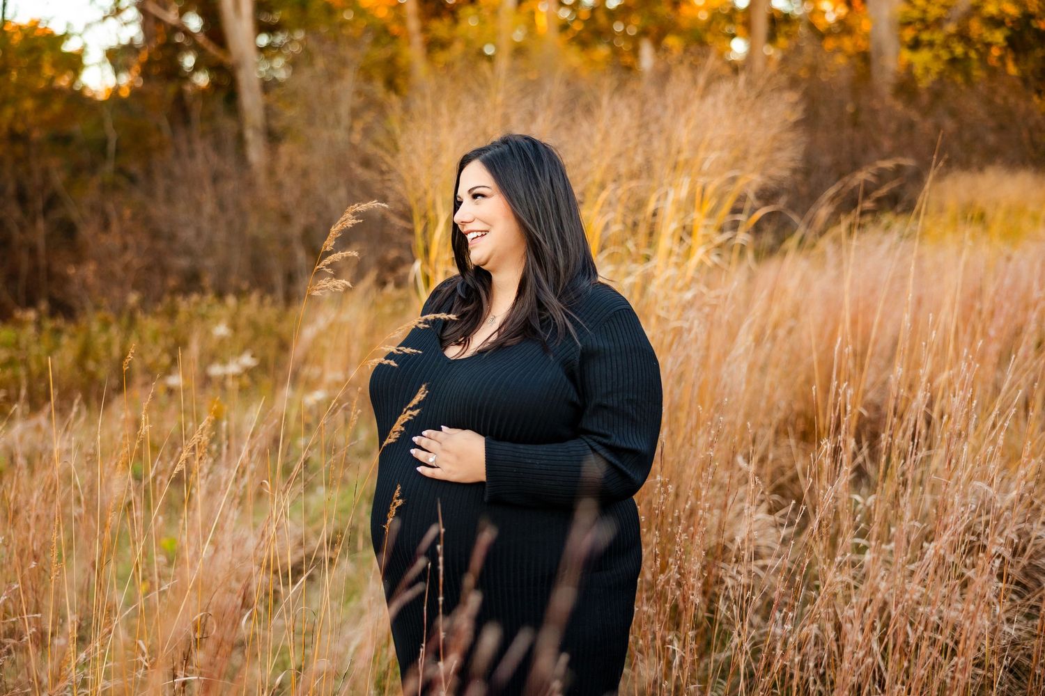 Fall maternity session in golden field with couple and dog at sunset.