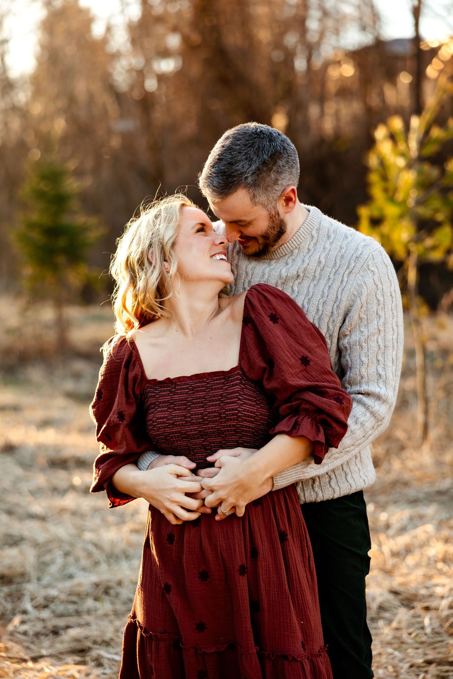 A couple shares an intimate moment in warm sunset light wearing coordinated winter outfits.