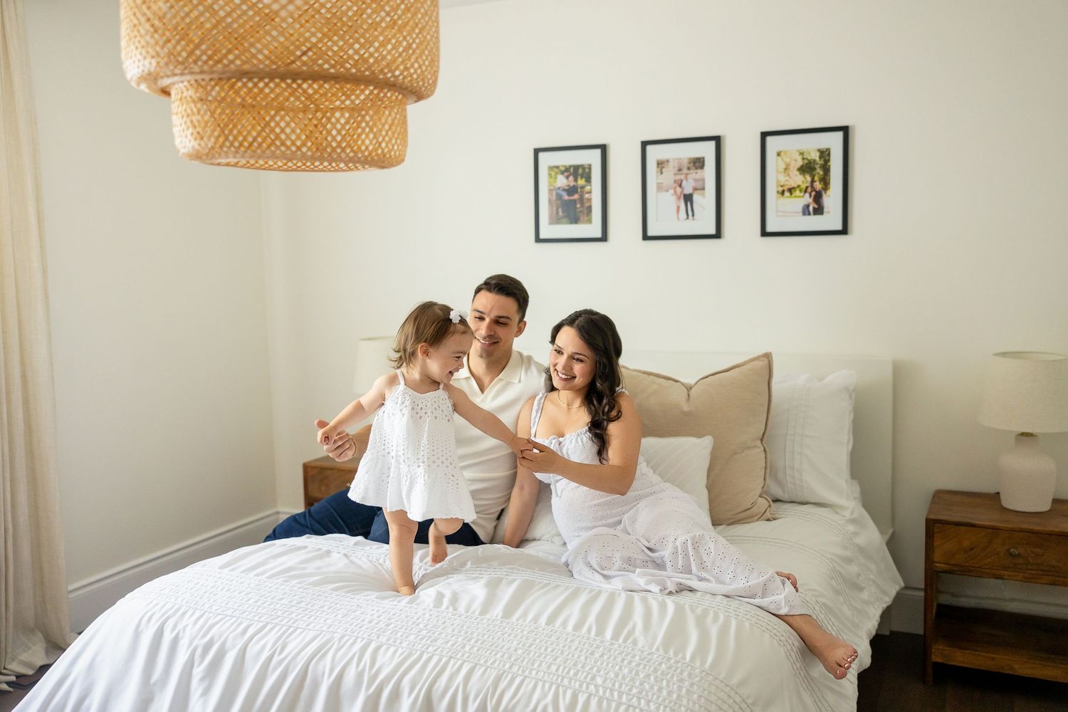 Modern bedroom photoshoot showing playful lifestyle moments on white bedding and pillows.