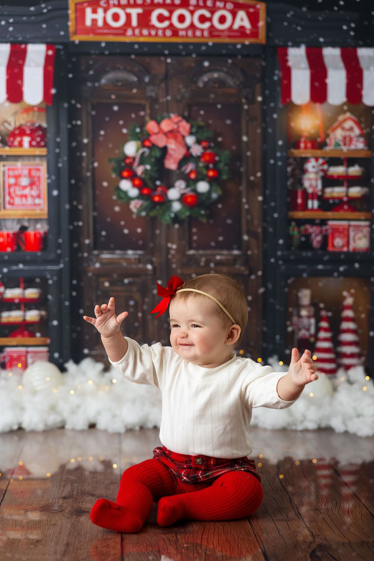 Holiday setup with red and white decorations, a wooden door backdrop, and hot cocoa signage.