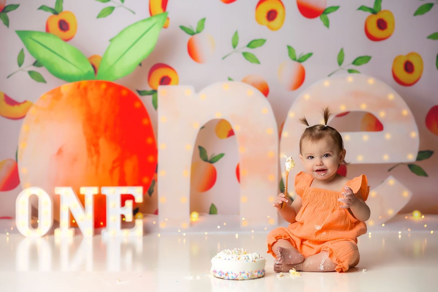 First birthday photoshoot with peach themed backdrop and matching outfit.