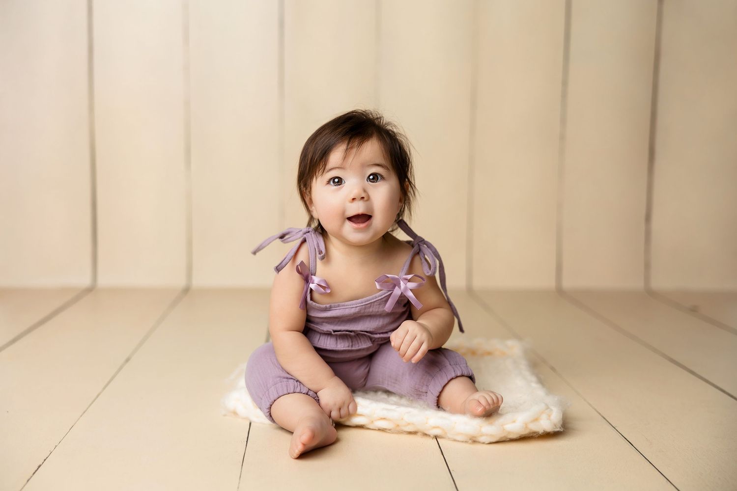 Studio portrait session with baby on neutral beige background.