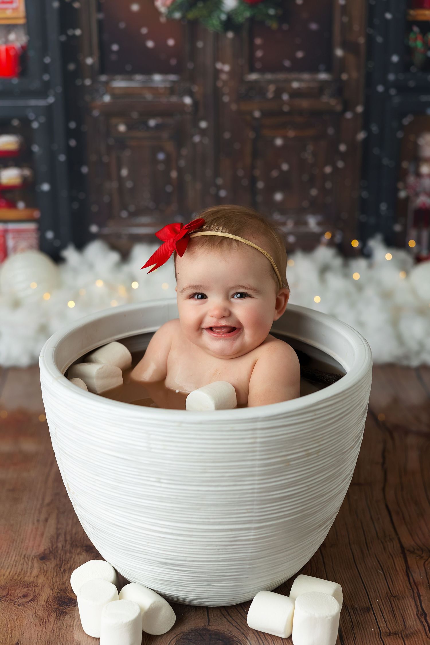 A decorative white ceramic mug setup with marshmallows against a cozy Christmas-themed background.