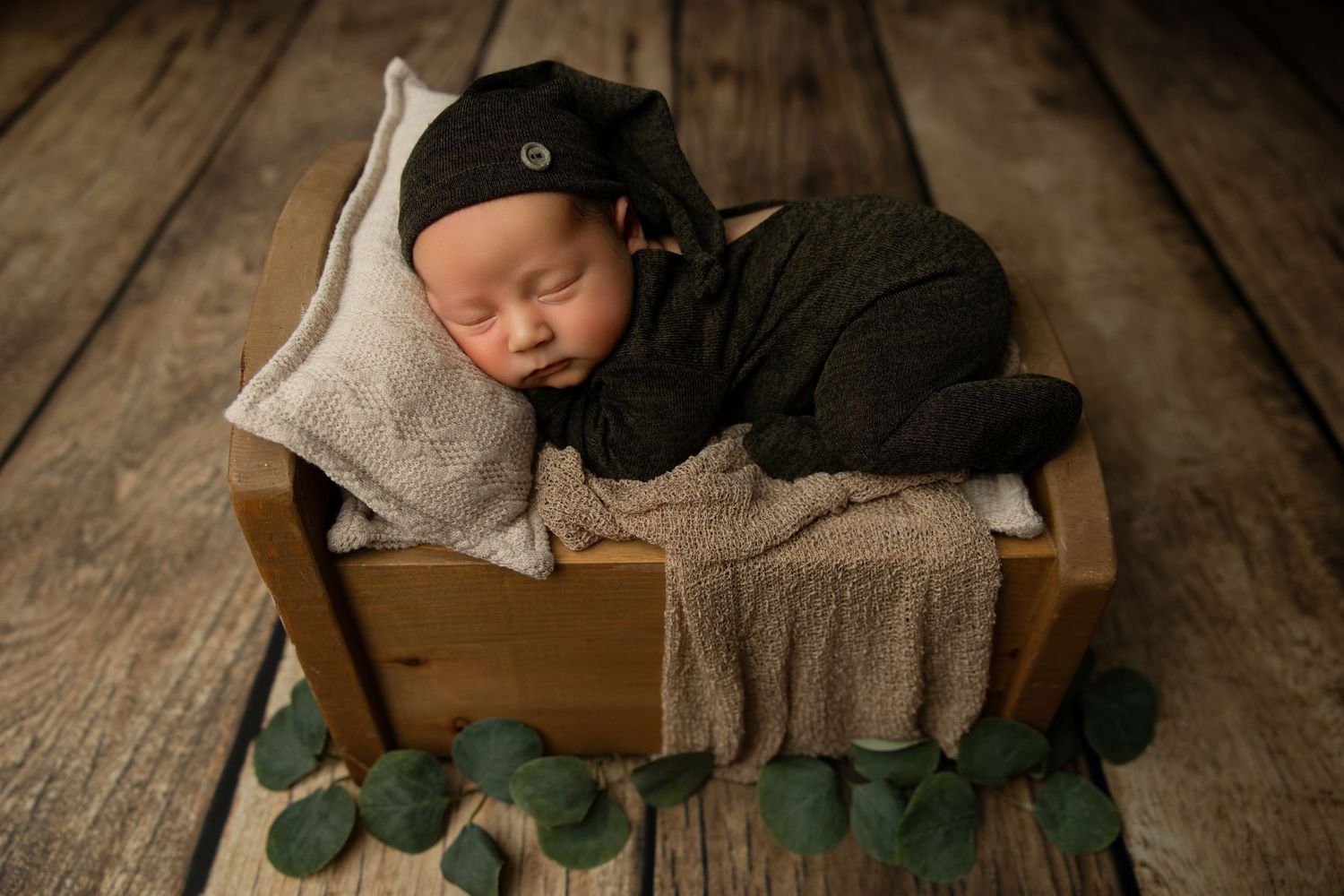 Tender parental hands holding sleeping newborn against grey background.