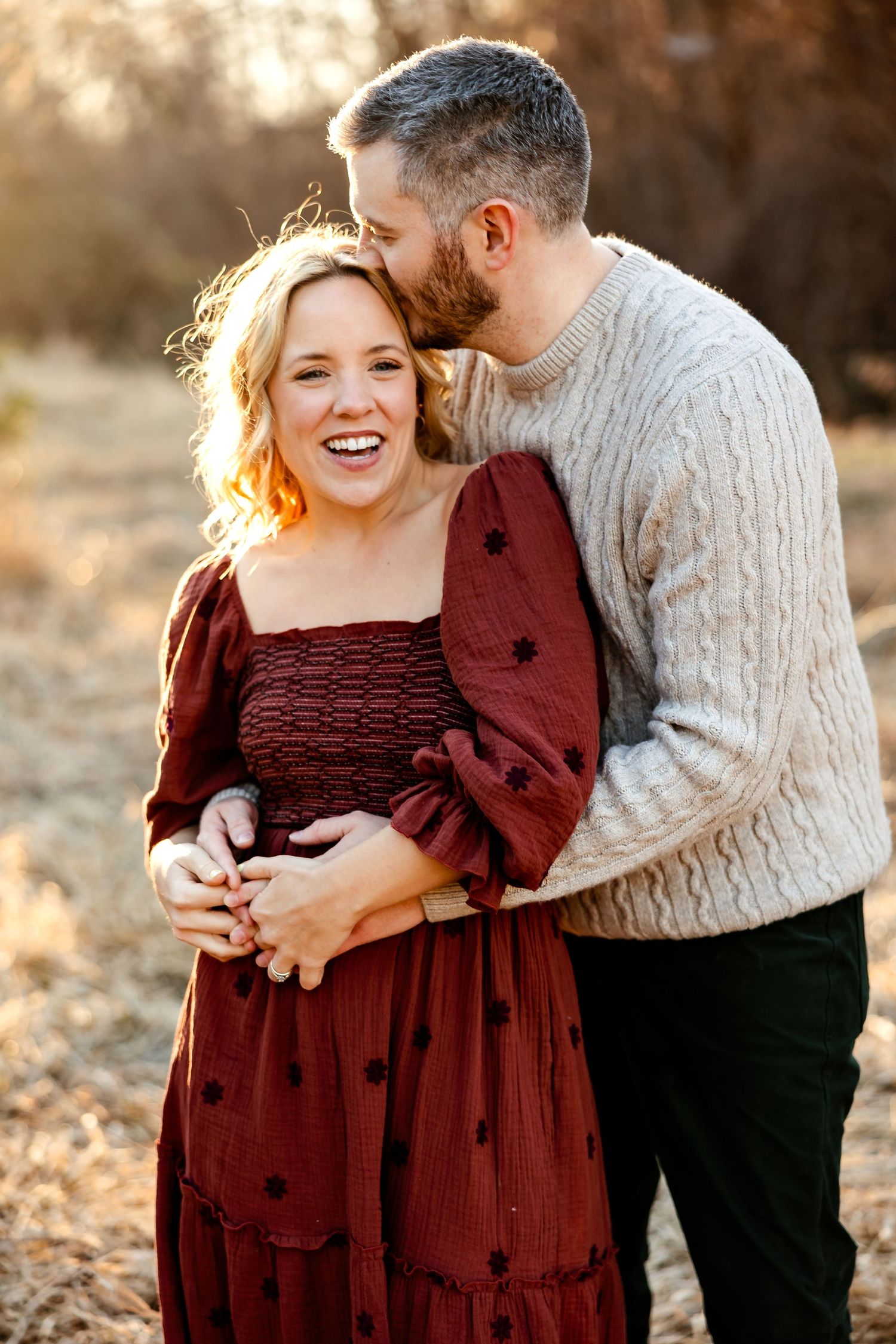 A couple shares a joyful laugh together during a sunset portrait session.