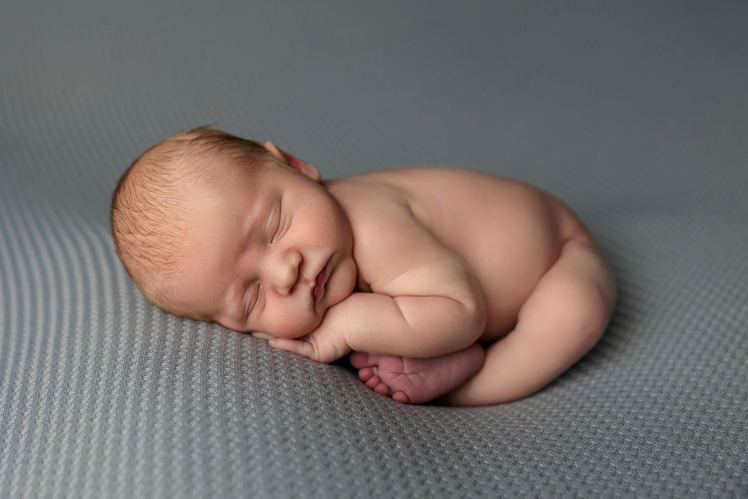 A series of peaceful newborn photography poses showing a sleeping baby on a soft gray textured backdrop.