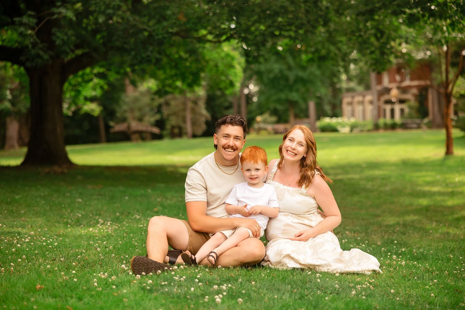 A family relaxing together on grass during a casual outdoor photo session.