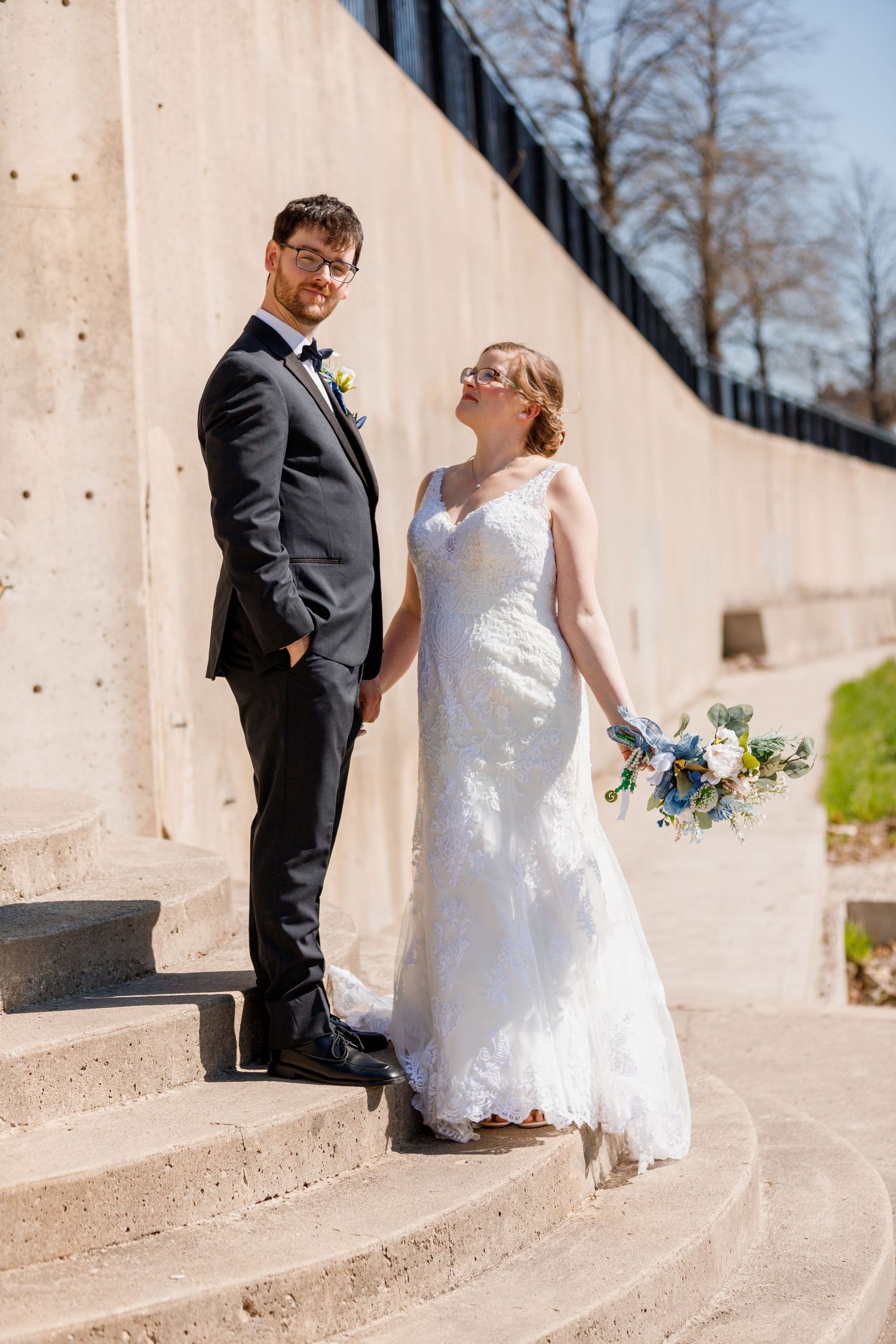 Elegant wedding portrait on curved concrete steps with classic formal attire.
