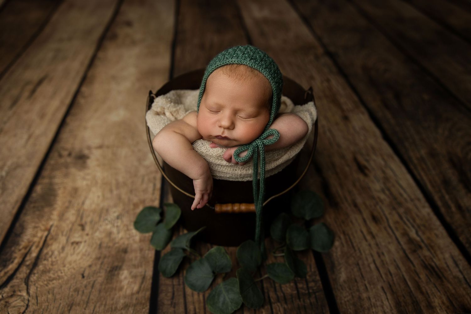 Rustic newborn photography featuring sleeping baby on vintage wooden floor.