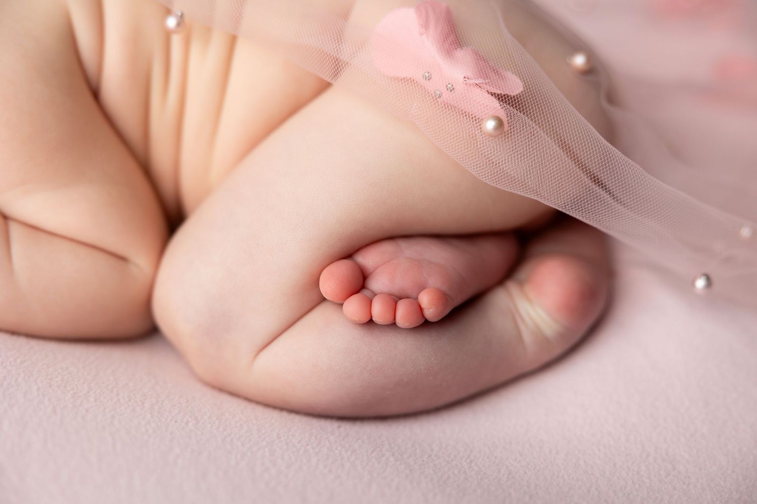 A delicate pink and lace background setting for newborn photography with soft floral accents.