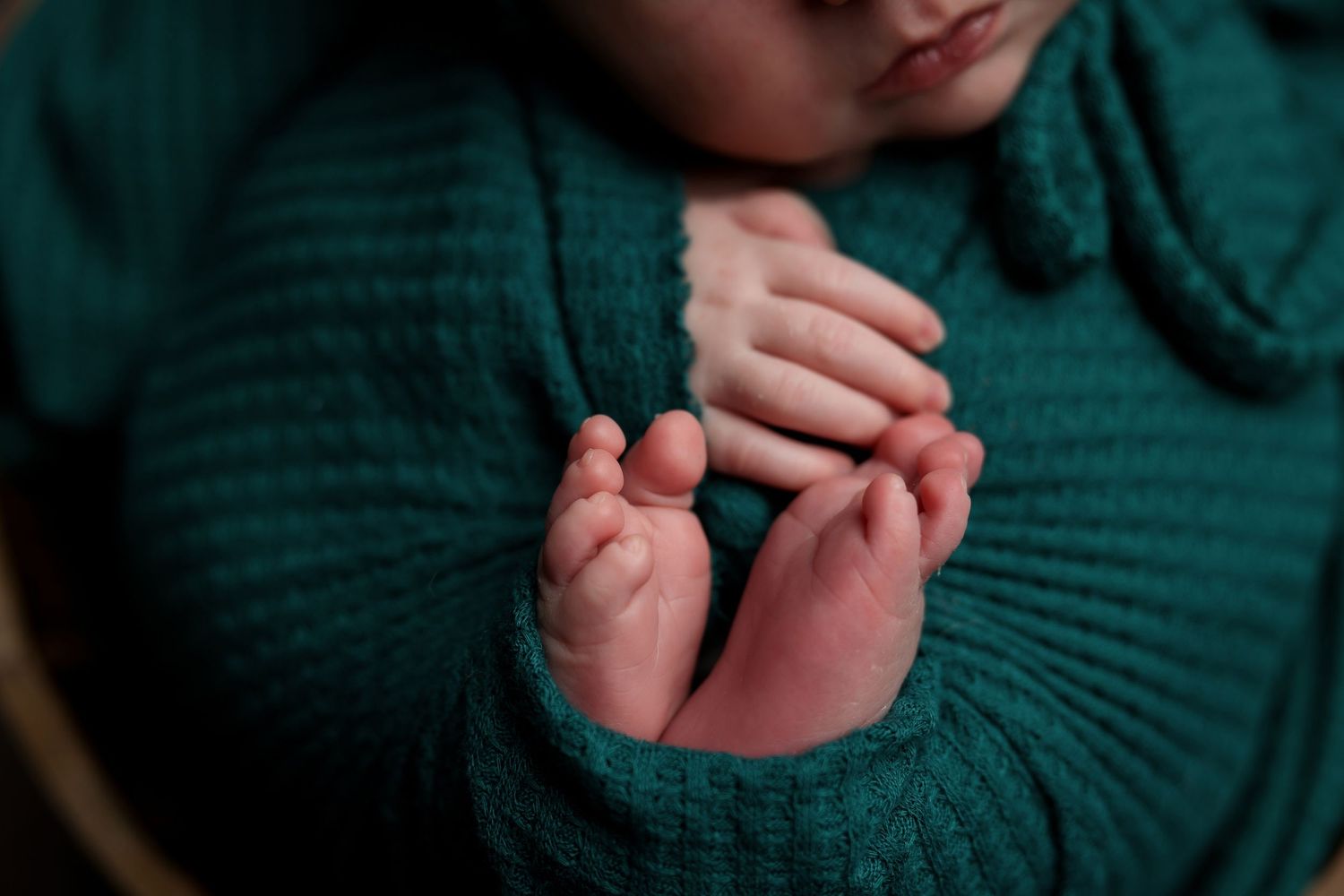 Close-up view of hands gently holding delicate items against a dark green knitted sweater background.