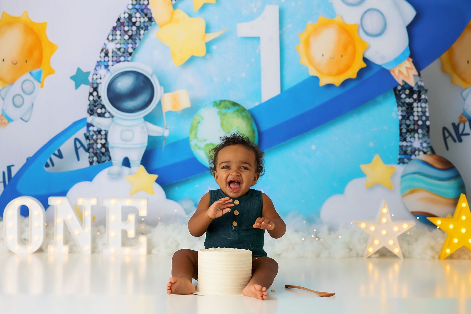 Outer space themed cake smash photo session with stars and planet decorations.