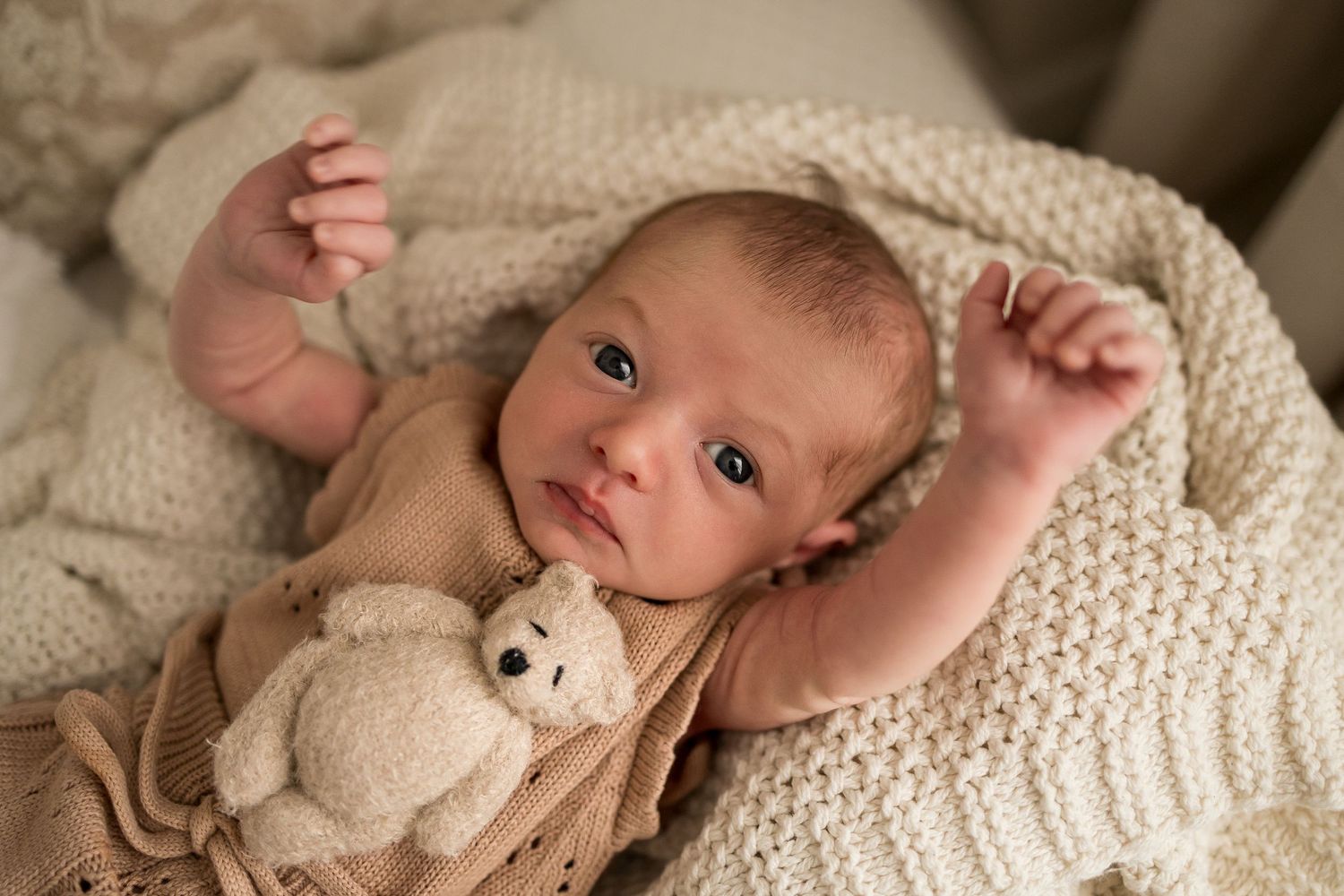 A series of tender newborn photography shots showing a baby nestled in cozy cream-colored blankets and textures.